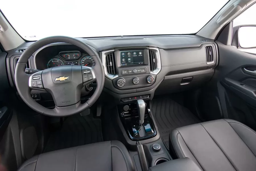 A customização da S10 Z71 se estende ao interior. Os apliques centrais do painel, os revestimentos das portas e do console são todos em tom escuro, criando um contraste atraente com os detalhes em cinza acetinado no habitáculo. O volante e os bancos contam com revestimento premium, e uma técnica de costura inglesa é utilizada para destacar as linhas claras e escuras, conferindo um charme extra aos assentos de tom escuro.